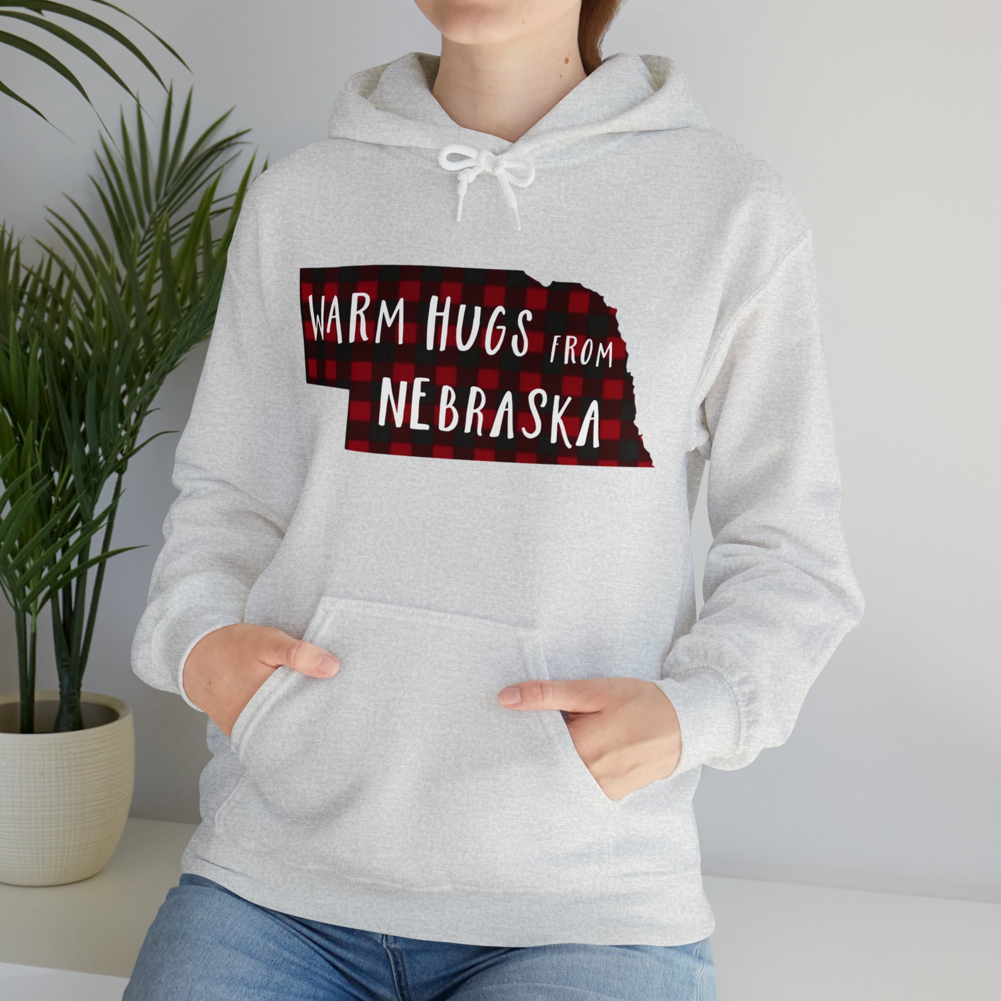 Light Gray hooded sweatshirt with a black and red buffalo plaid design in the shape of Nebraska that says, "Warm Hugs from Nebraska"