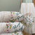 Stack of cream colored plush blankets with "Hugs & Prayers" and a floral wreath detail