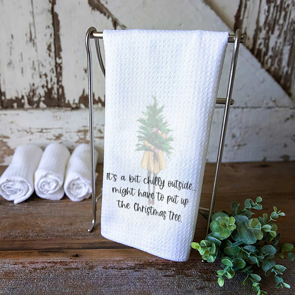 Dishtowel  with a faint image of a girl holding a Christmas Tree and the words, "it's a bit chilly outside... might have to put up the Christmas tree."
