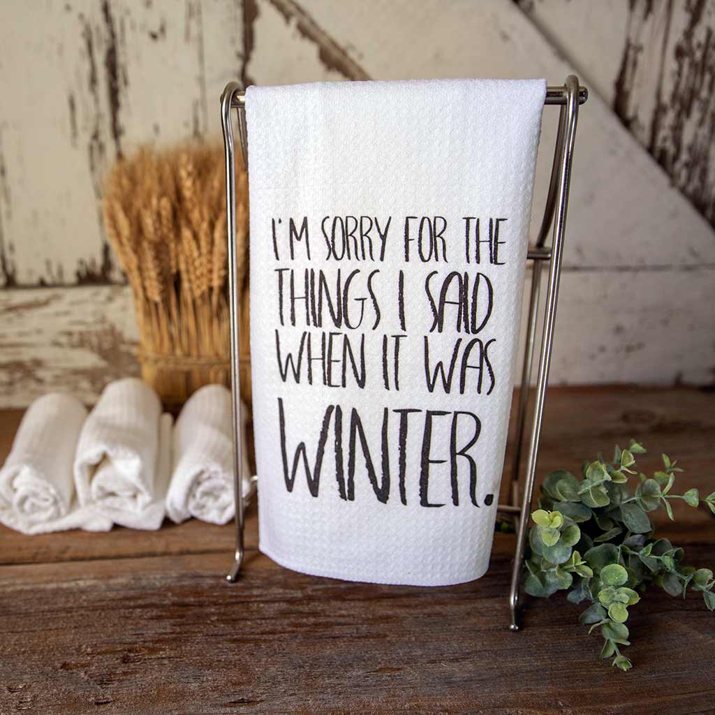 "I'm Sorry for the things I said when it was winter." in black all capital letters in a hand written font printed on a white waffle weave towel.