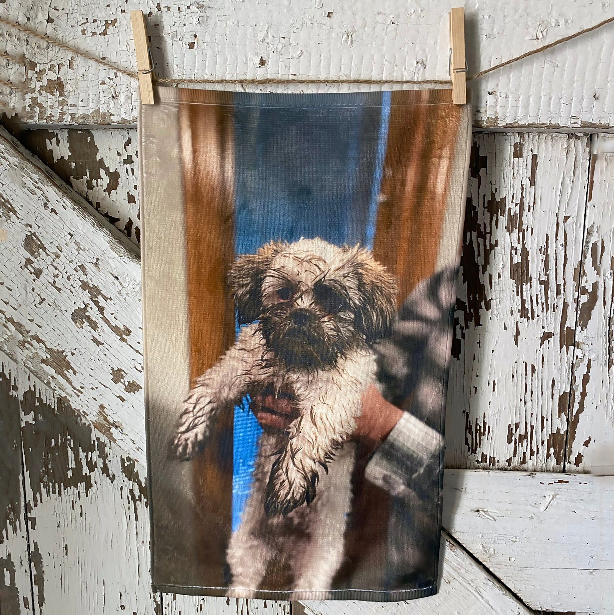 A small towel with a photo of a very muddy puppy printed on it.